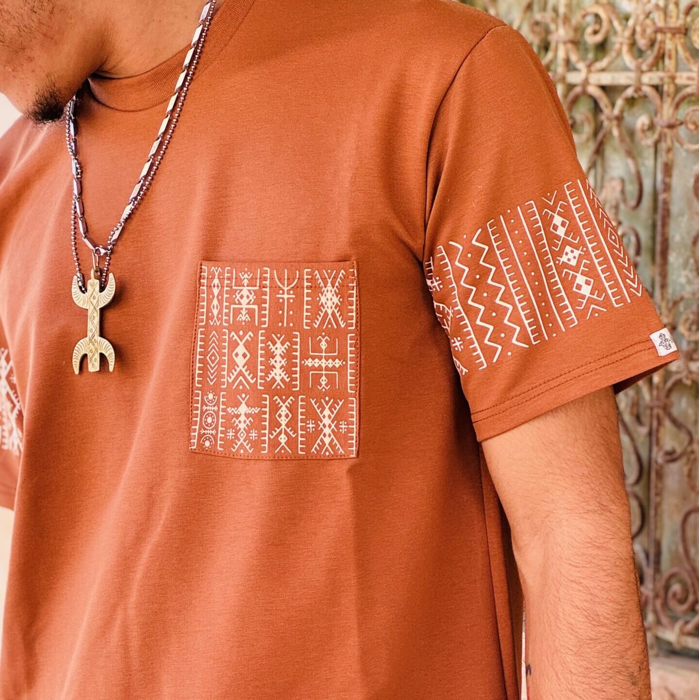 Terracotta Moroccan Amazigh T-shirt with white geometric embroidery on the chest, sleeves, and hem