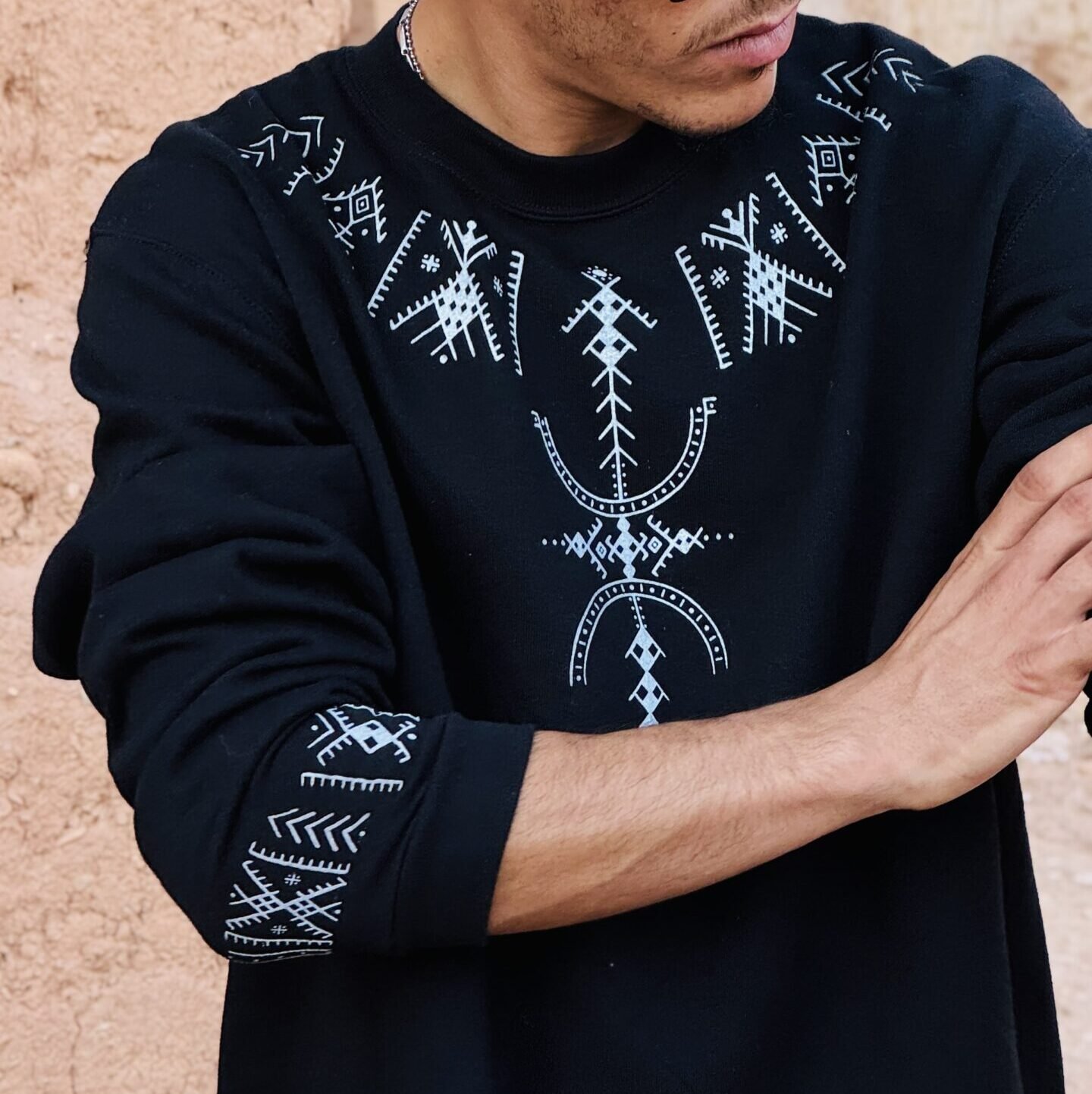 Black sweatshirt with white Amazigh geometric motifs across the chest, shoulders and sleeve cuff