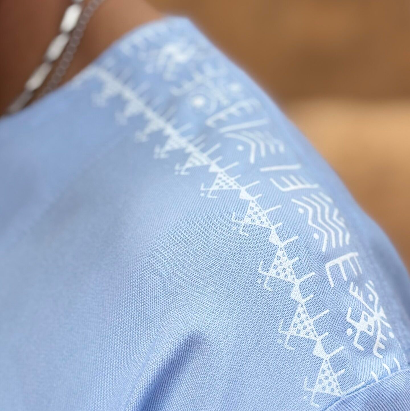 Light blue Moroccan Amazigh garment with white geometric embroidery across the shoulder