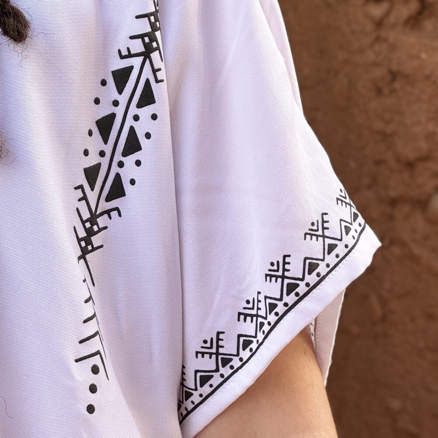 White Moroccan Amazigh dress with black geometric motifs and traditional symbols on the sleeve