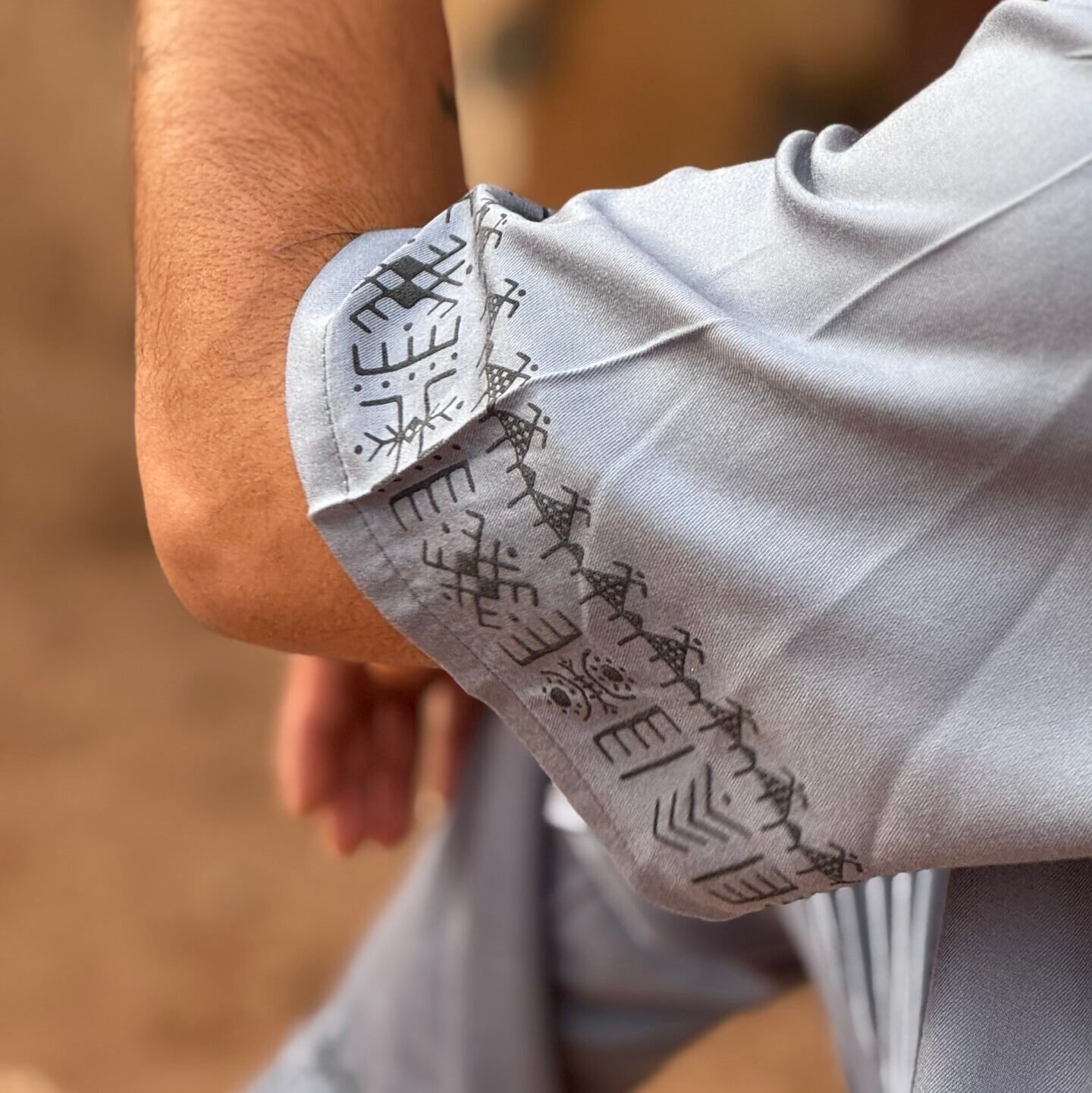 Gray Moroccan shirt sleeve with black Amazigh-inspired symbols embroidered along the cuff