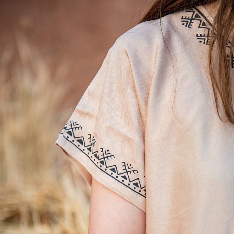 Cream-colored Amazigh gandora with dark geometric patterns on the collar and sleeve