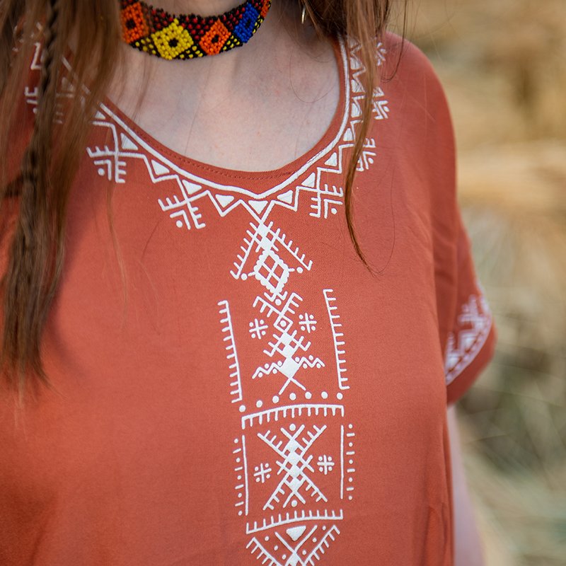 Terracotta Amazigh gandora with white geometric patterns around the neckline and front
