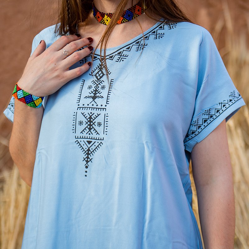 Light blue Amazigh-inspired gandora with dark geometric patterns on the neckline, chest, and sleeves
