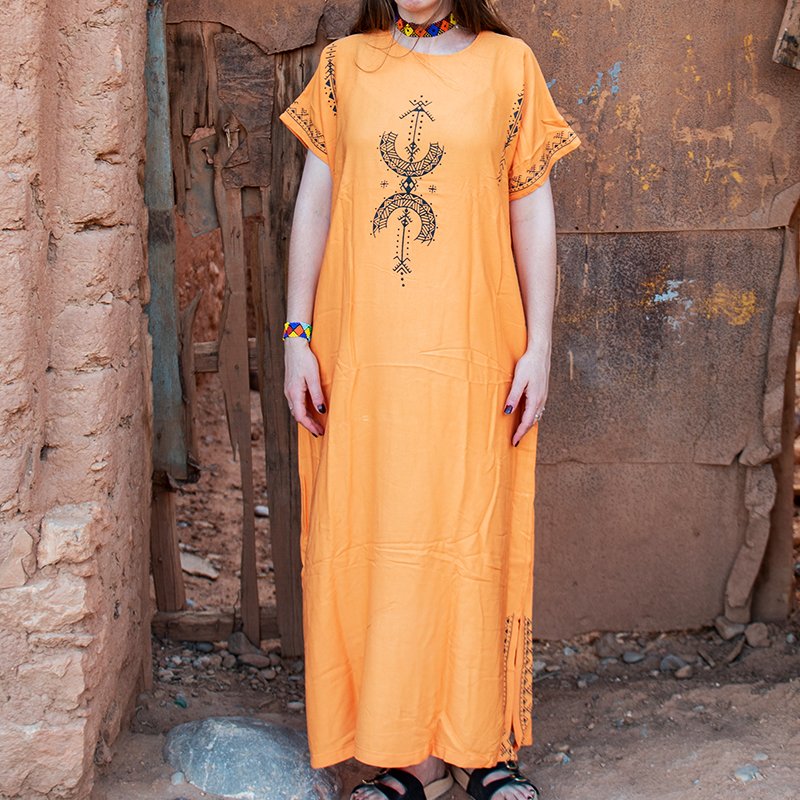 Orange Amazigh gandora with black AZA symbols and geometric patterns on the front and sleeves