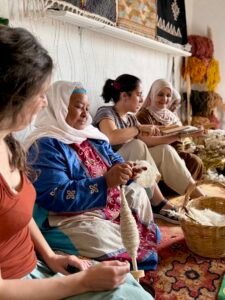 Traditional Moroccan wool spinning workshop with visitors learning artisanal textile techniques