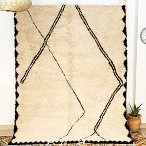 Tapis artisanal écru conçu par Afusart, tissé à la main par Malika, avec motifs amazighs noirs et touches colorées.