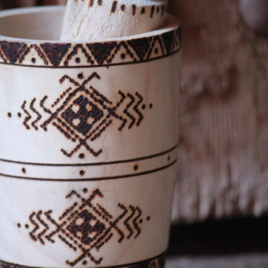 Mortier et pilon artisanaux en bois de tamarinier, décorés à la main de motifs géométriques amazighs.