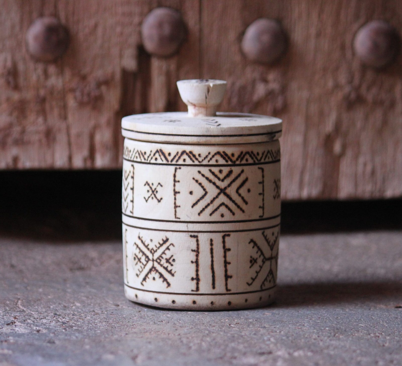 Boîte cylindrique artisanale en bois de tamarinier avec couvercle, décorée de motifs géométriques amazighs.