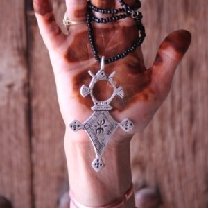 Pendentif amazigh en métal plaqué argent avec motif gravé, monté sur un collier de perles noires.