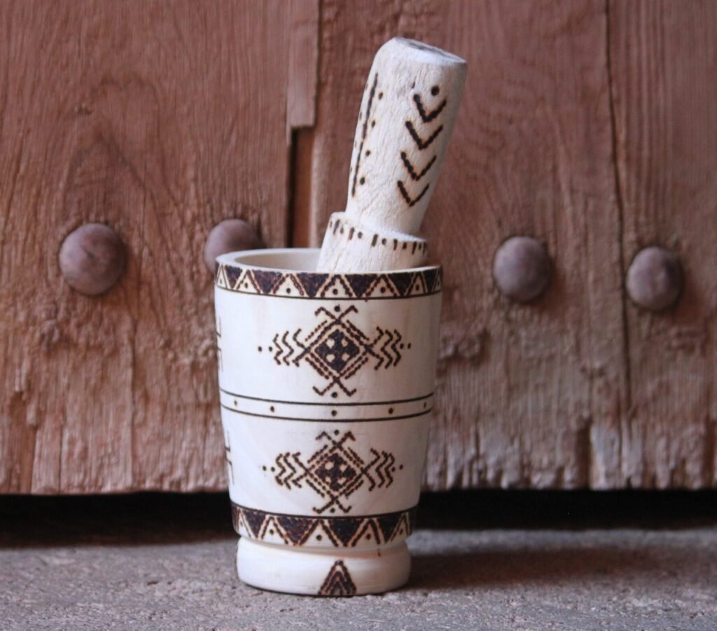 Mortier et pilon artisanaux en bois de tamarinier, décorés à la main de motifs géométriques amazighs.