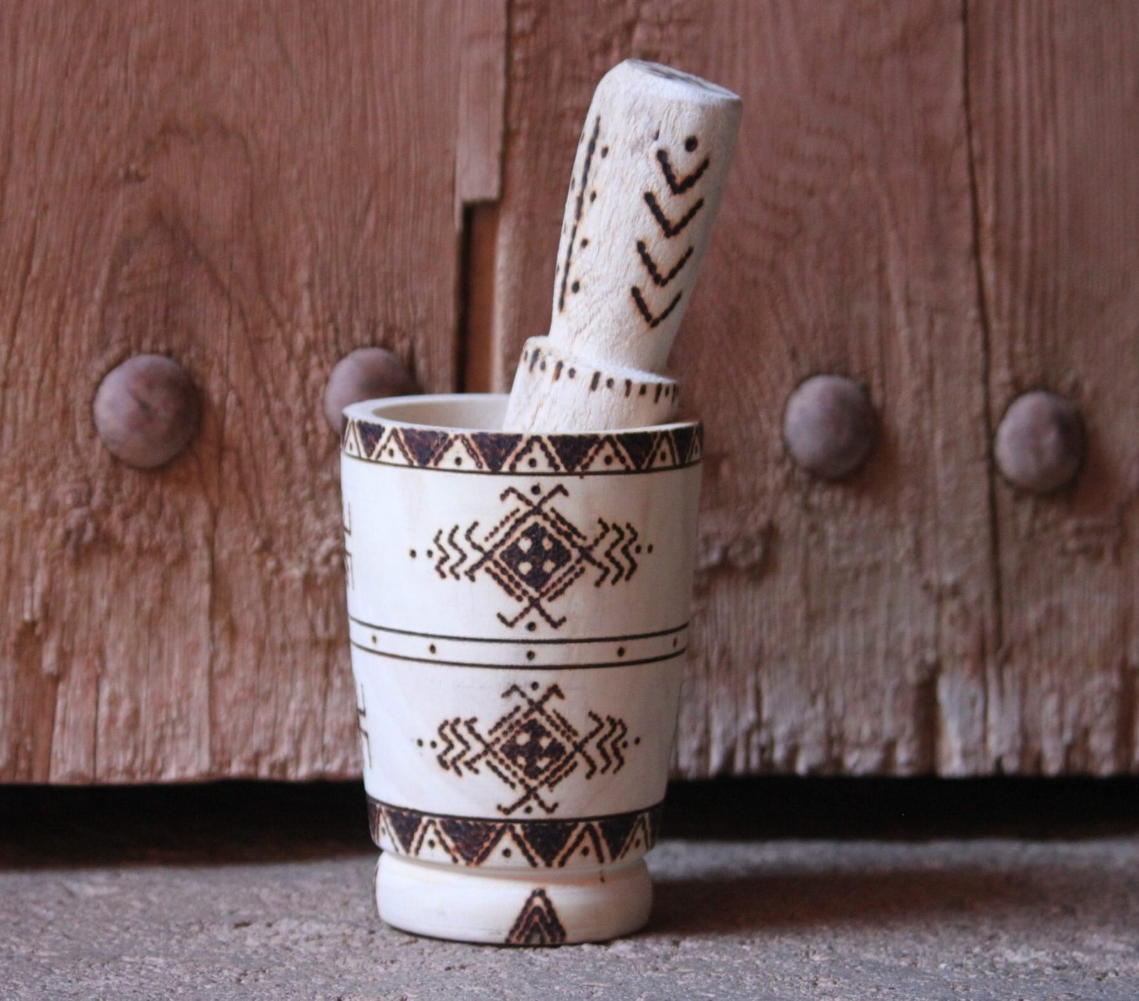 Mortier et pilon artisanaux en bois de tamarinier, décorés à la main de motifs géométriques amazighs.