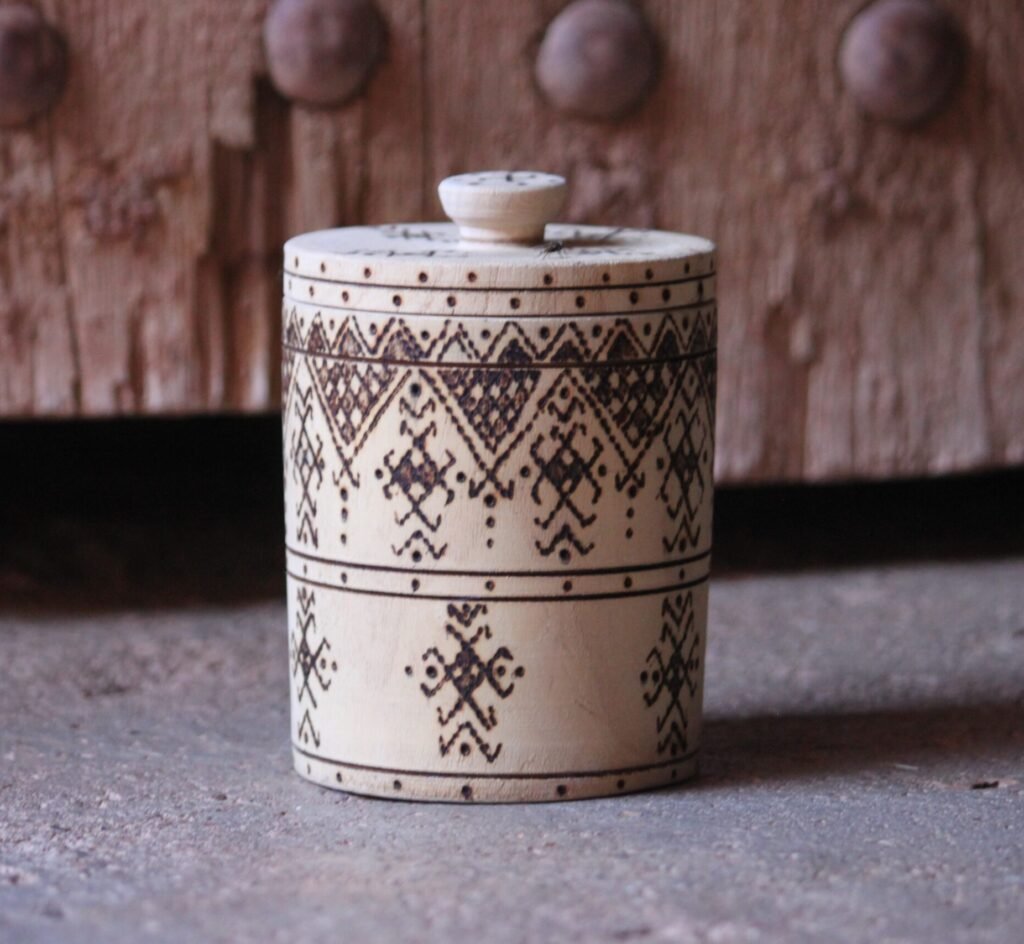 Boîte cylindrique artisanale en bois de tamarinier avec couvercle, décorée de motifs géométriques amazighs.