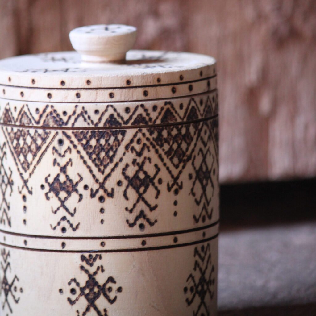 Boîte cylindrique artisanale en bois de tamarinier avec couvercle, décorée de motifs géométriques amazighs.