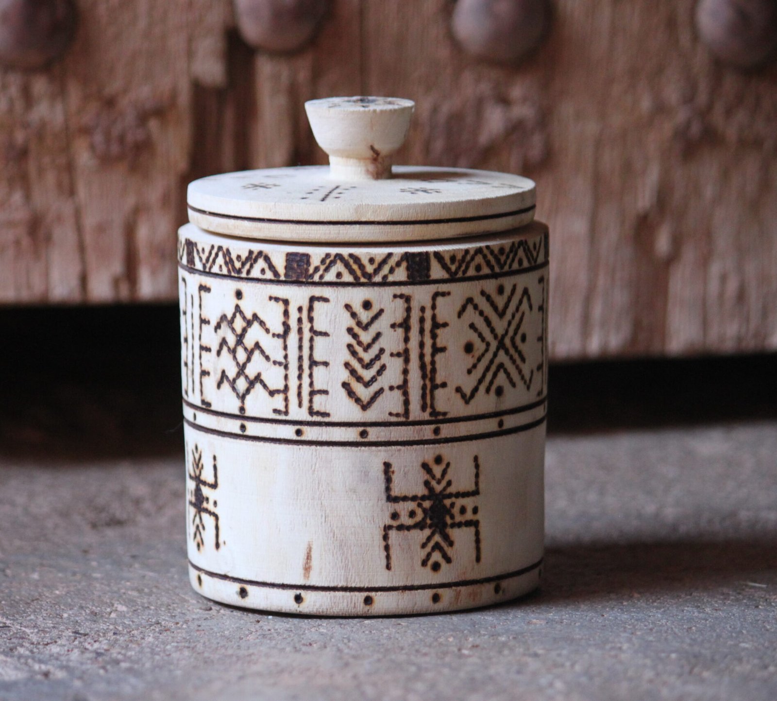 Boîte cylindrique artisanale en bois de tamarinier avec couvercle, décorée de motifs géométriques amazighs.