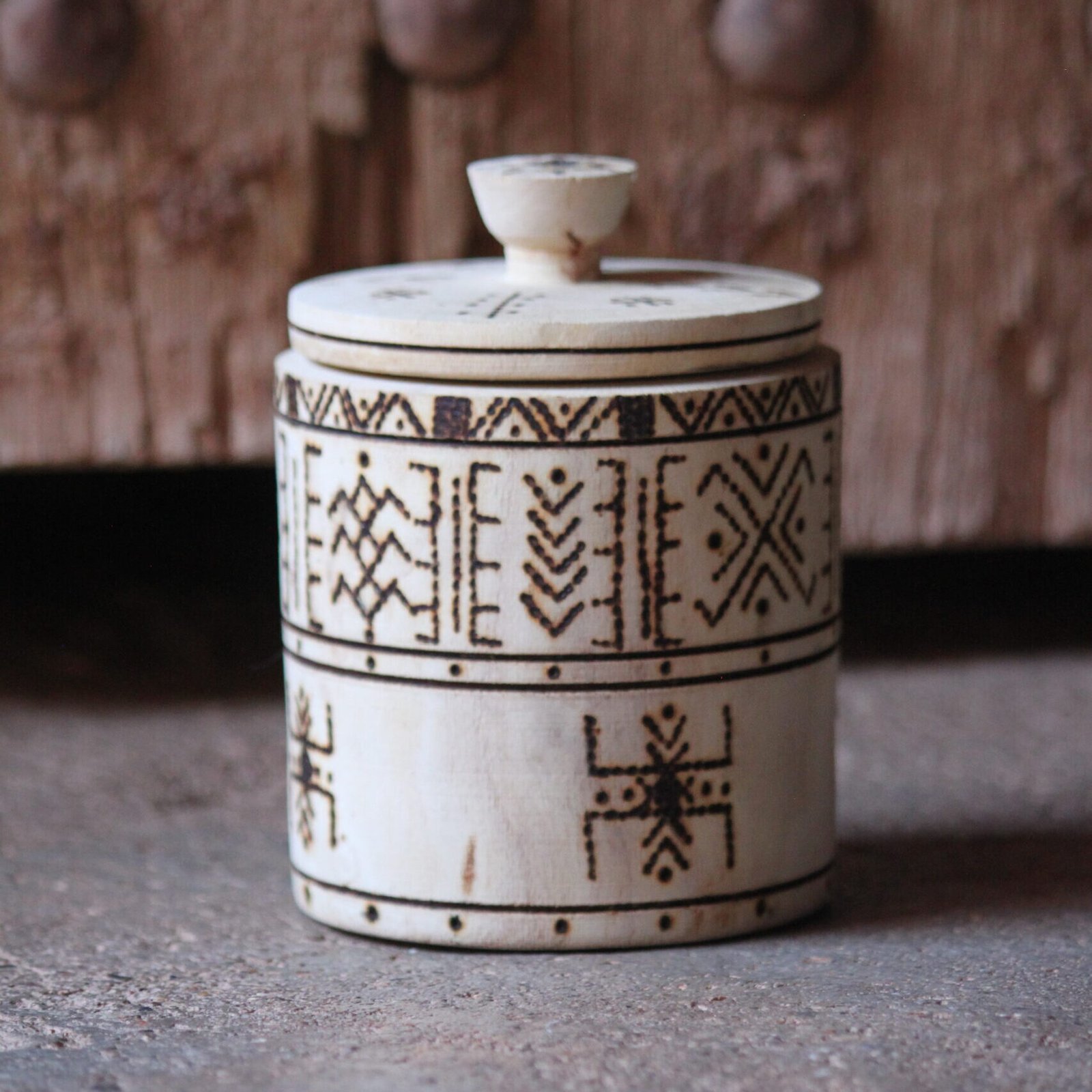 Boîte cylindrique artisanale en bois de tamarinier avec couvercle, décorée de motifs géométriques amazighs.