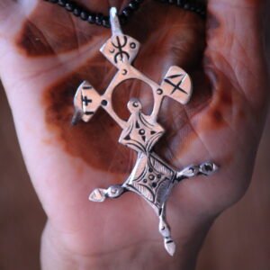 Pendentif amazigh en métal plaqué argent avec motif gravé, monté sur un collier de perles noires.