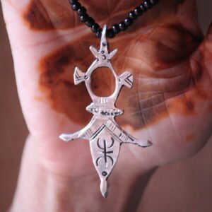 Pendentif amazigh en métal plaqué argent avec motif gravé, monté sur un collier de perles noires.