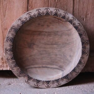 Grande assiette artisanale en bois de noyer, décorée de motifs géométriques amazighs sur le pourtour.