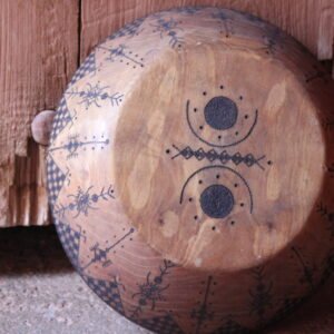 Grande assiette artisanale en bois, décorée de motifs géométriques amazighs sur le pourtour.