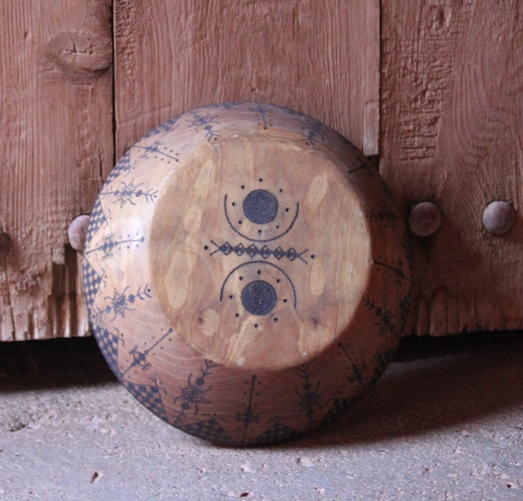 Grande assiette artisanale en bois de noyer, décorée de motifs géométriques amazighs sur le pourtour.
