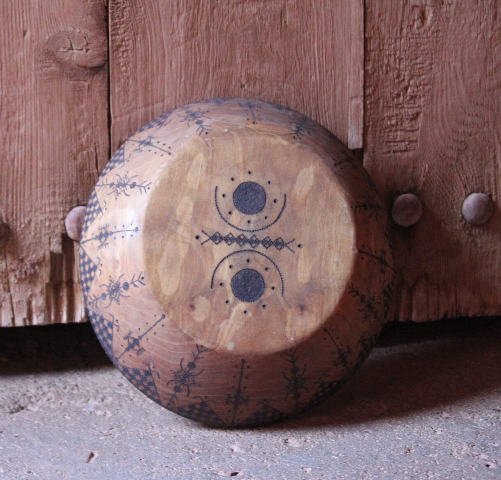 Grande assiette artisanale en bois de noyer, décorée de motifs géométriques amazighs sur le pourtour.