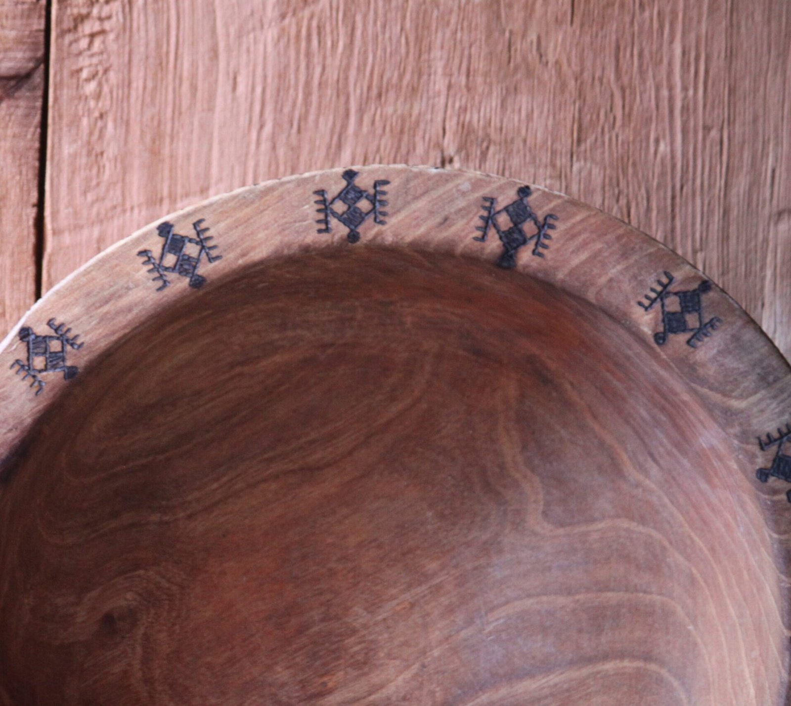 Grande assiette artisanale en bois de noyer, décorée de motifs géométriques amazighs sur le pourtour.