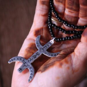 Pendentif amazigh en métal plaqué argent avec motif gravé, monté sur un collier de perles noires.