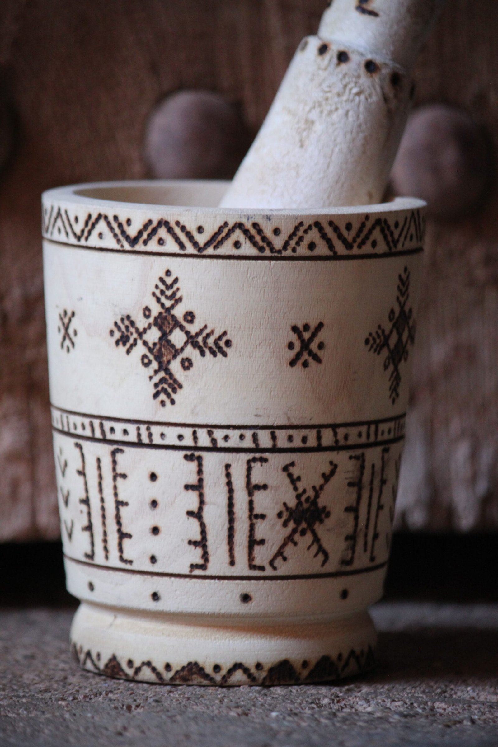 Mortier et pilon artisanaux en bois de tamarinier, décorés à la main de motifs géométriques amazighs.