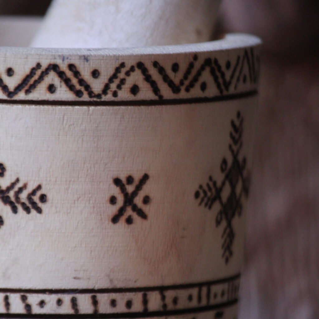 Mortier et pilon artisanaux en bois de tamarinier, décorés à la main de motifs géométriques amazighs.
