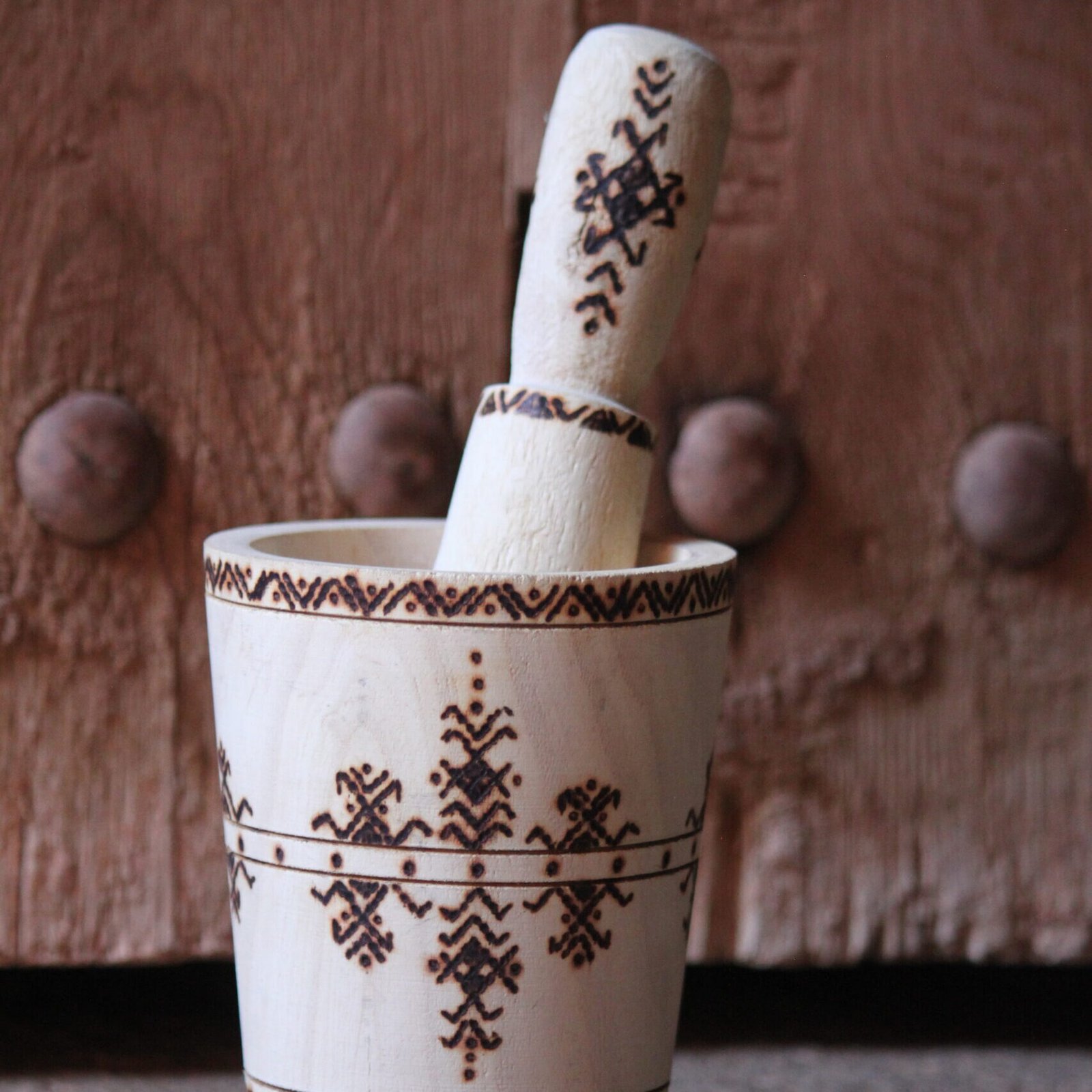Mortier et pilon artisanaux en bois de tamarinier, décorés à la main de motifs géométriques amazighs.
