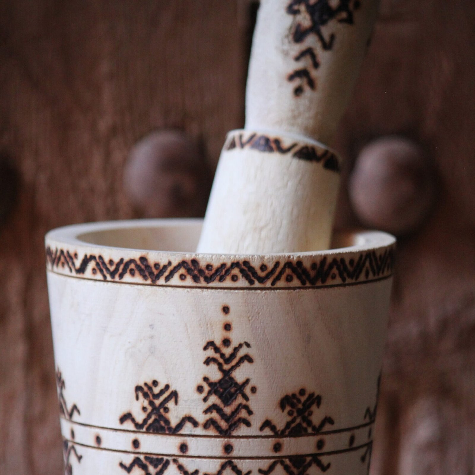 Mortier et pilon artisanaux en bois de tamarinier, décorés à la main de motifs géométriques amazighs.