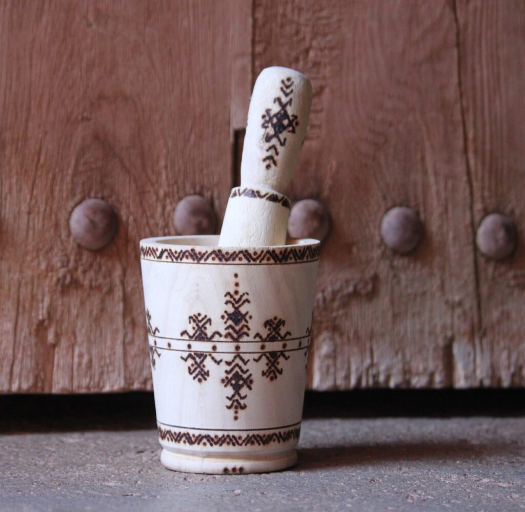 Mortier et pilon artisanaux en bois de tamarinier, décorés à la main de motifs géométriques amazighs.