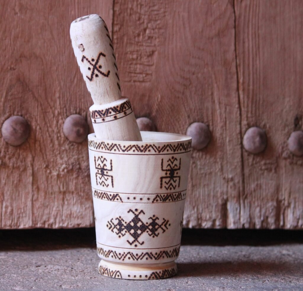 Mortier et pilon artisanaux en bois de tamarinier, décorés à la main de motifs géométriques amazighs.