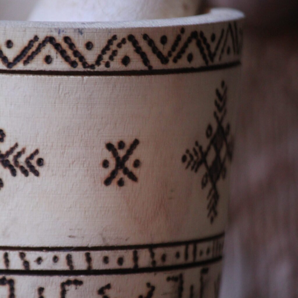 Mortier et pilon artisanaux en bois de tamarinier, décorés à la main de motifs géométriques amazighs.
