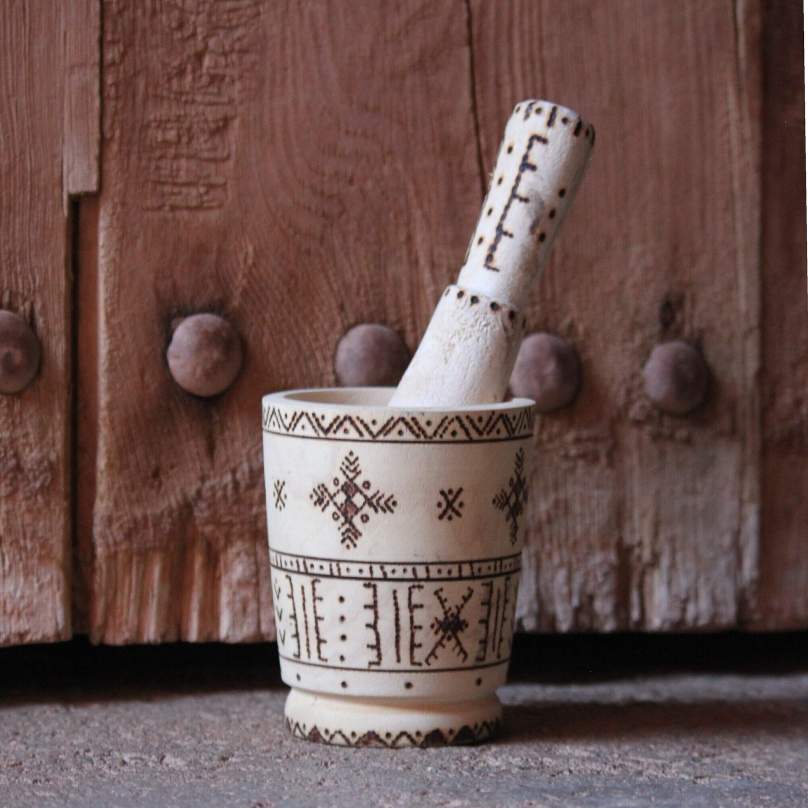 Mortier et pilon artisanaux en bois de tamarinier, décorés à la main de motifs géométriques amazighs.