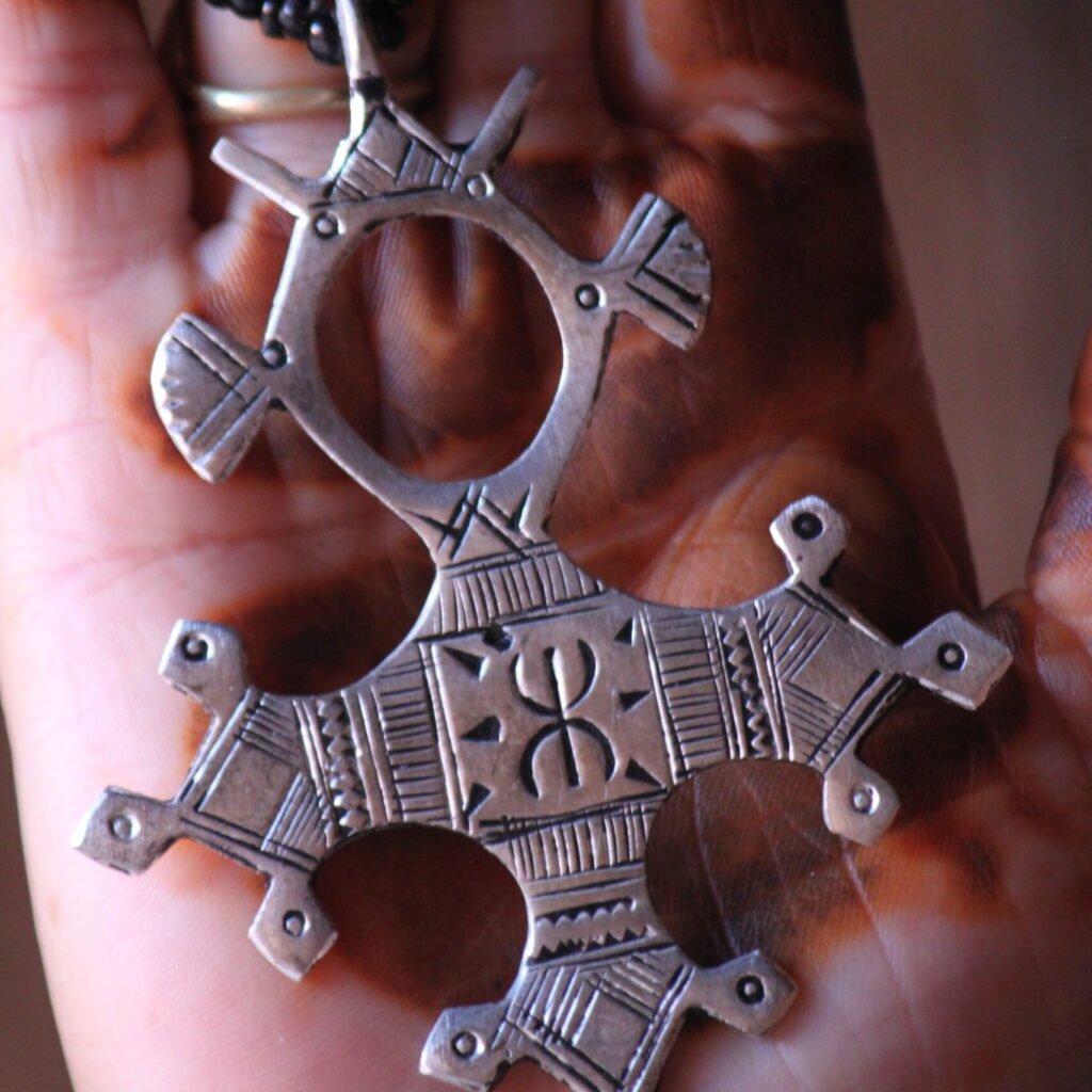 Pendentif amazigh en métal plaqué argent avec motif gravé, monté sur un collier de perles noires.