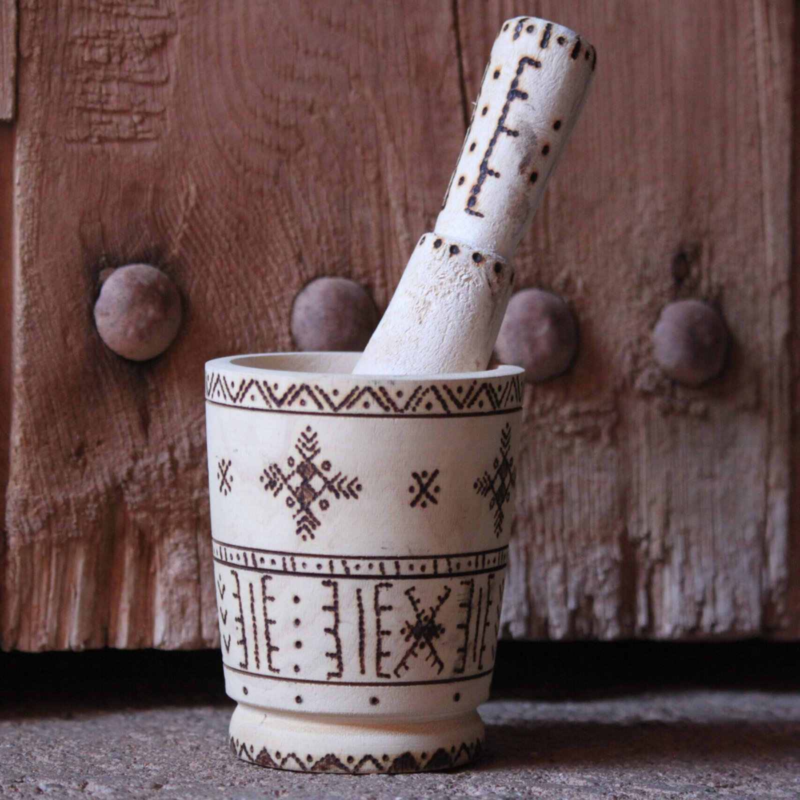 Mortier et pilon artisanaux en bois de tamarinier, décorés à la main de motifs géométriques amazighs.