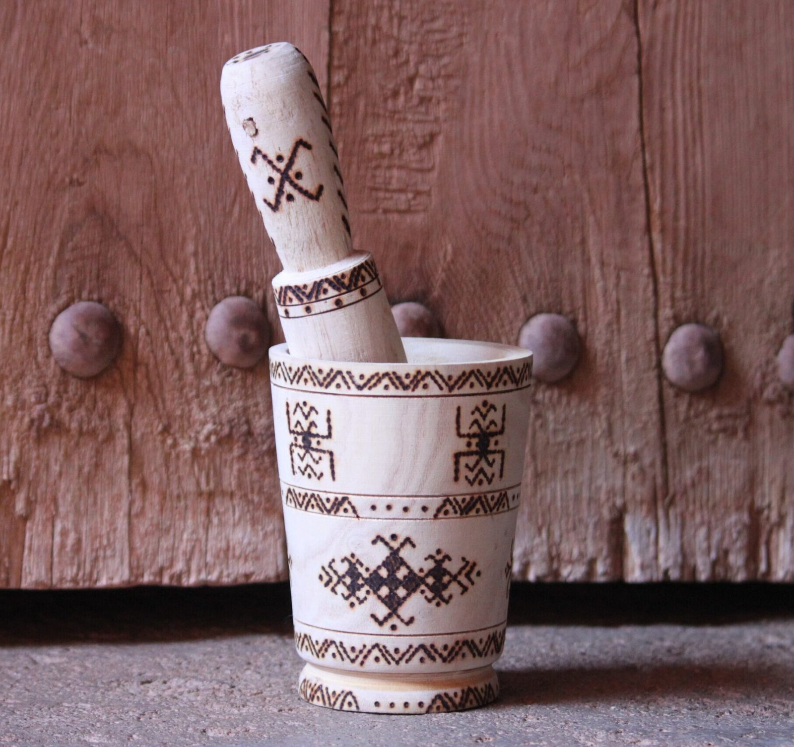 Mortier et pilon artisanaux en bois de tamarinier, décorés à la main de motifs géométriques amazighs.