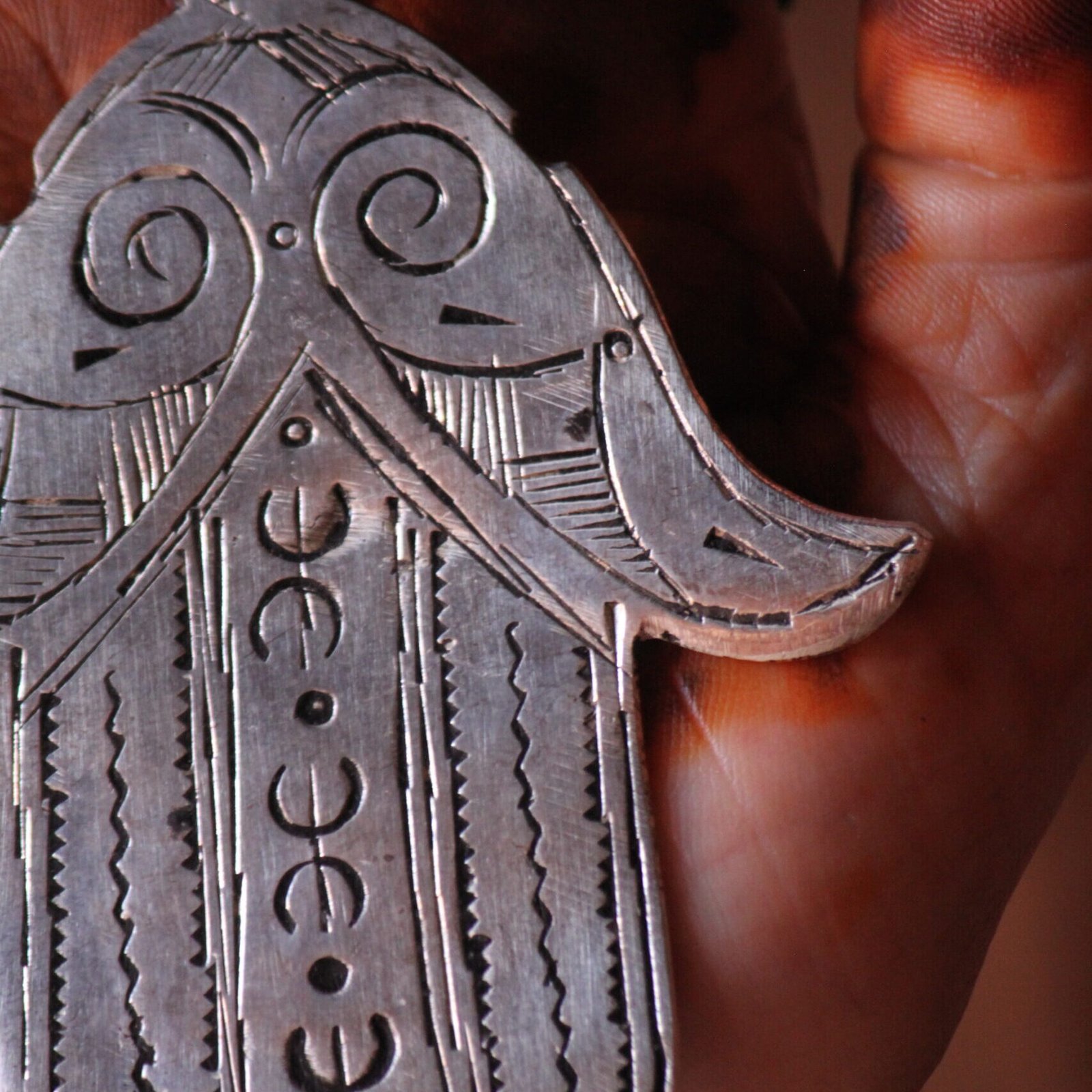 Pendentif amazigh en métal plaqué argent avec motif gravé, monté sur un collier de perles noires.