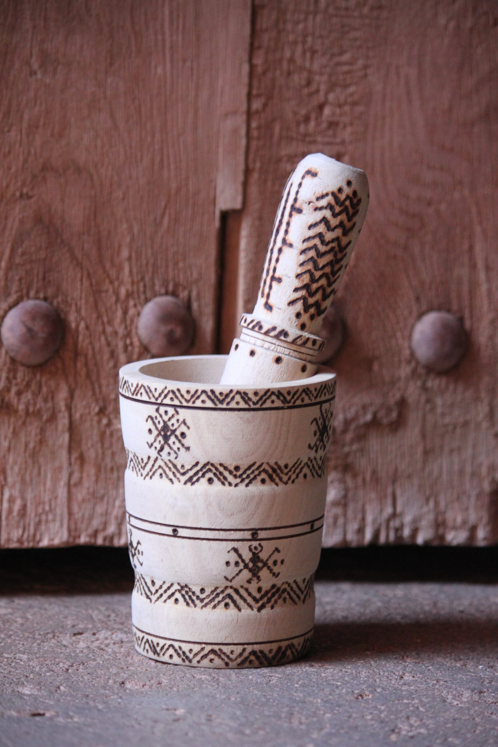 Mortier et pilon artisanaux en bois de tamarinier, décorés à la main de motifs géométriques amazighs.