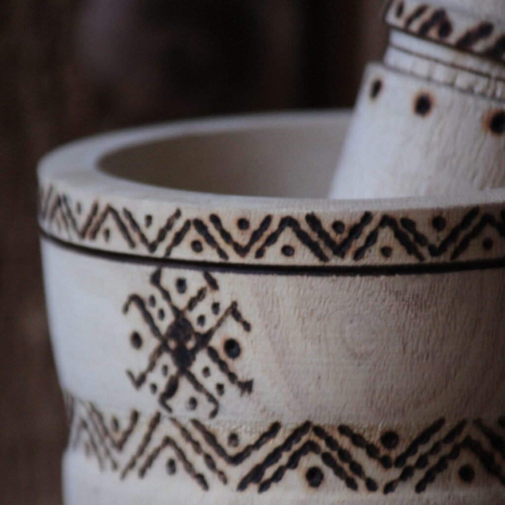 Mortier et pilon artisanaux en bois de tamarinier, décorés à la main de motifs géométriques amazighs.