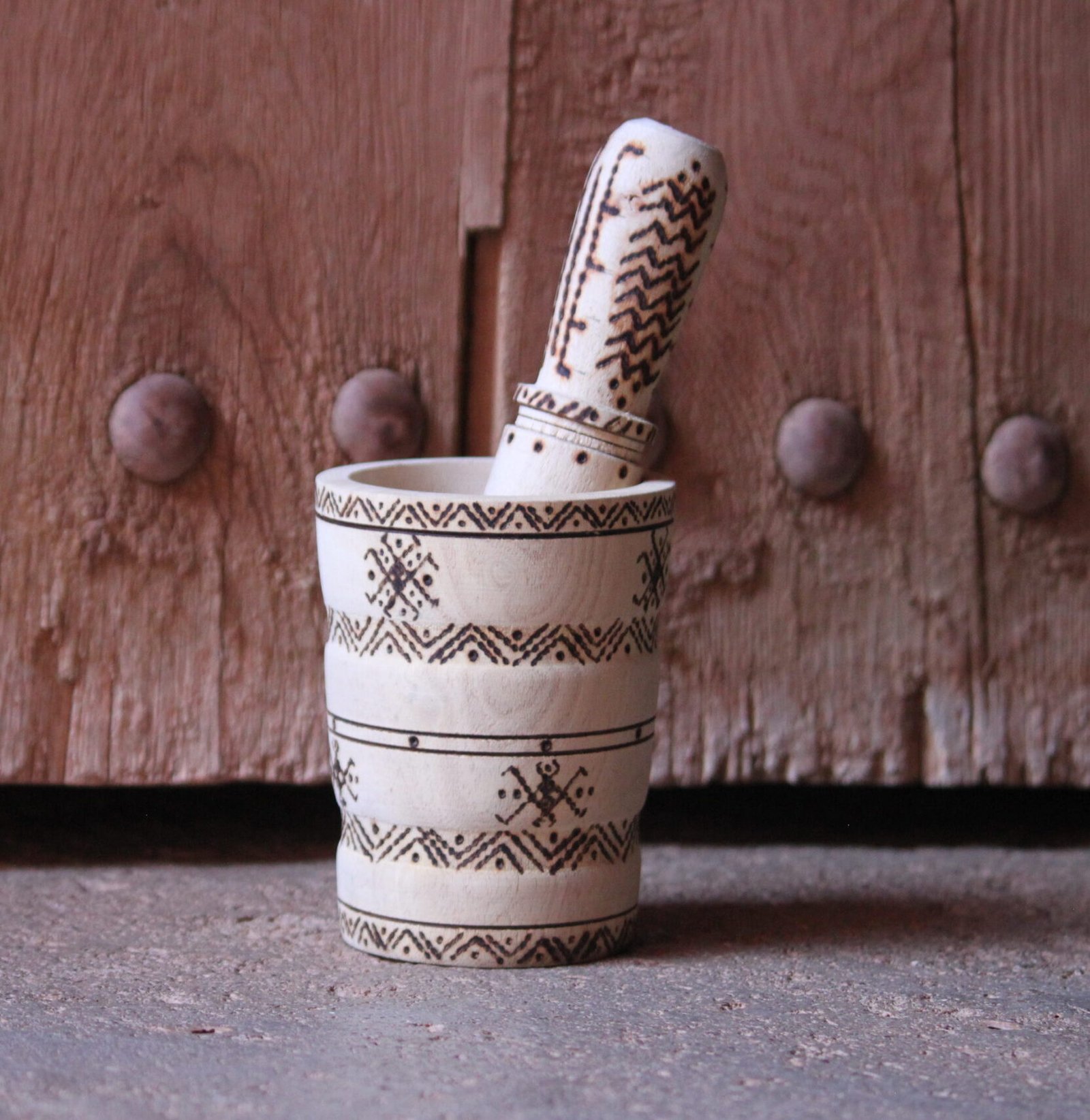 Mortier et pilon artisanaux en bois de tamarinier, décorés à la main de motifs géométriques amazighs.