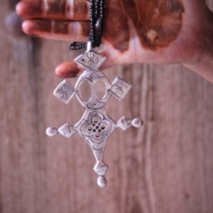 Pendentif amazigh en métal plaqué argent avec motif gravé, monté sur un collier de perles noires.