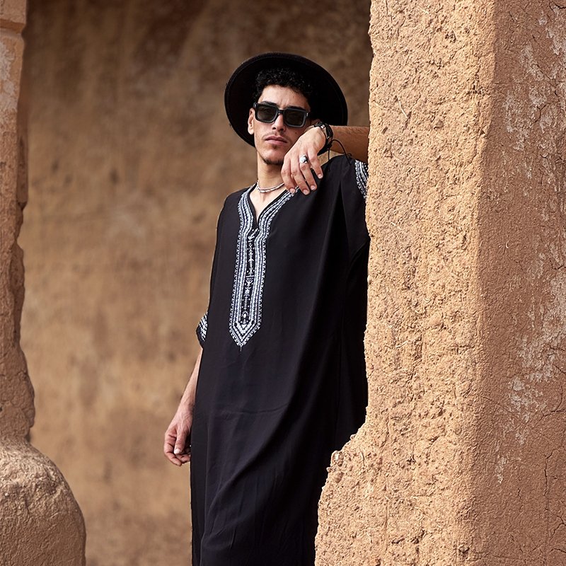 Homme portant une gandoura amazighe noire Afusart, décorée de motifs traditionnels contrastés.