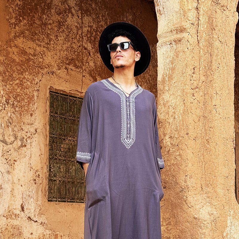Homme portant une gandoura amazighe grise Afusart avec des motifs décoratifs d’inspiration amazighe.