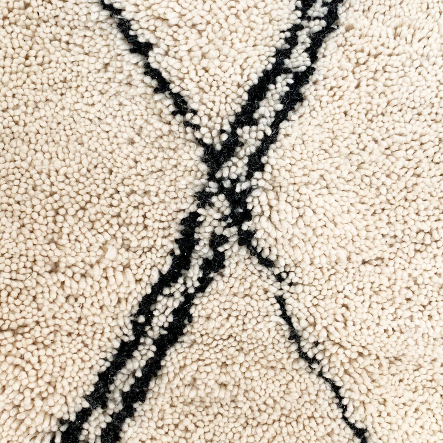 Tapis artisanal écru conçu par Afusart, tissé à la main par Malika, avec motifs amazighs noirs et touches colorées.