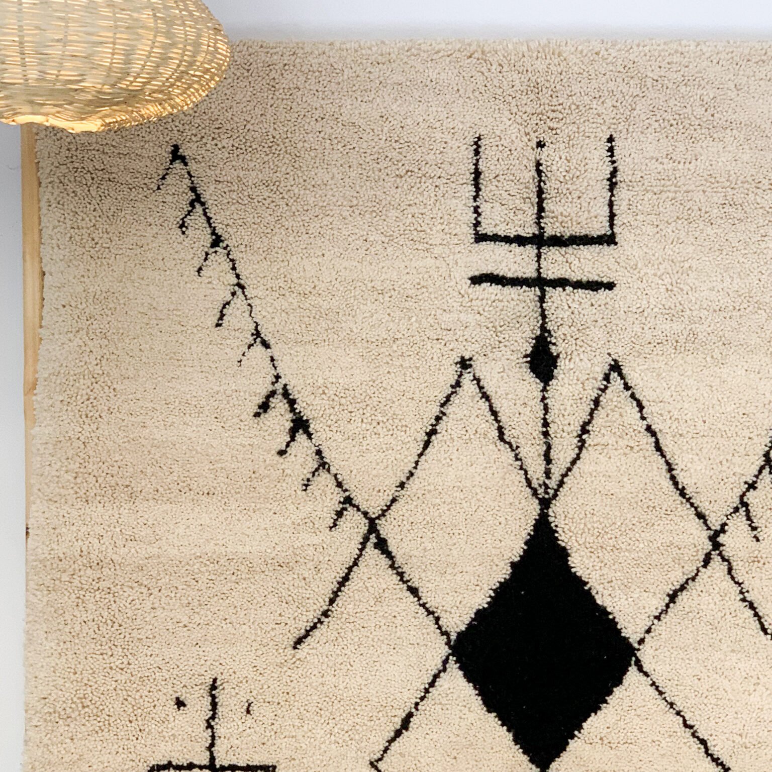 Tapis artisanal écru conçu par Afusart, tissé à la main par Malika, avec motifs amazighs noirs et touches colorées.