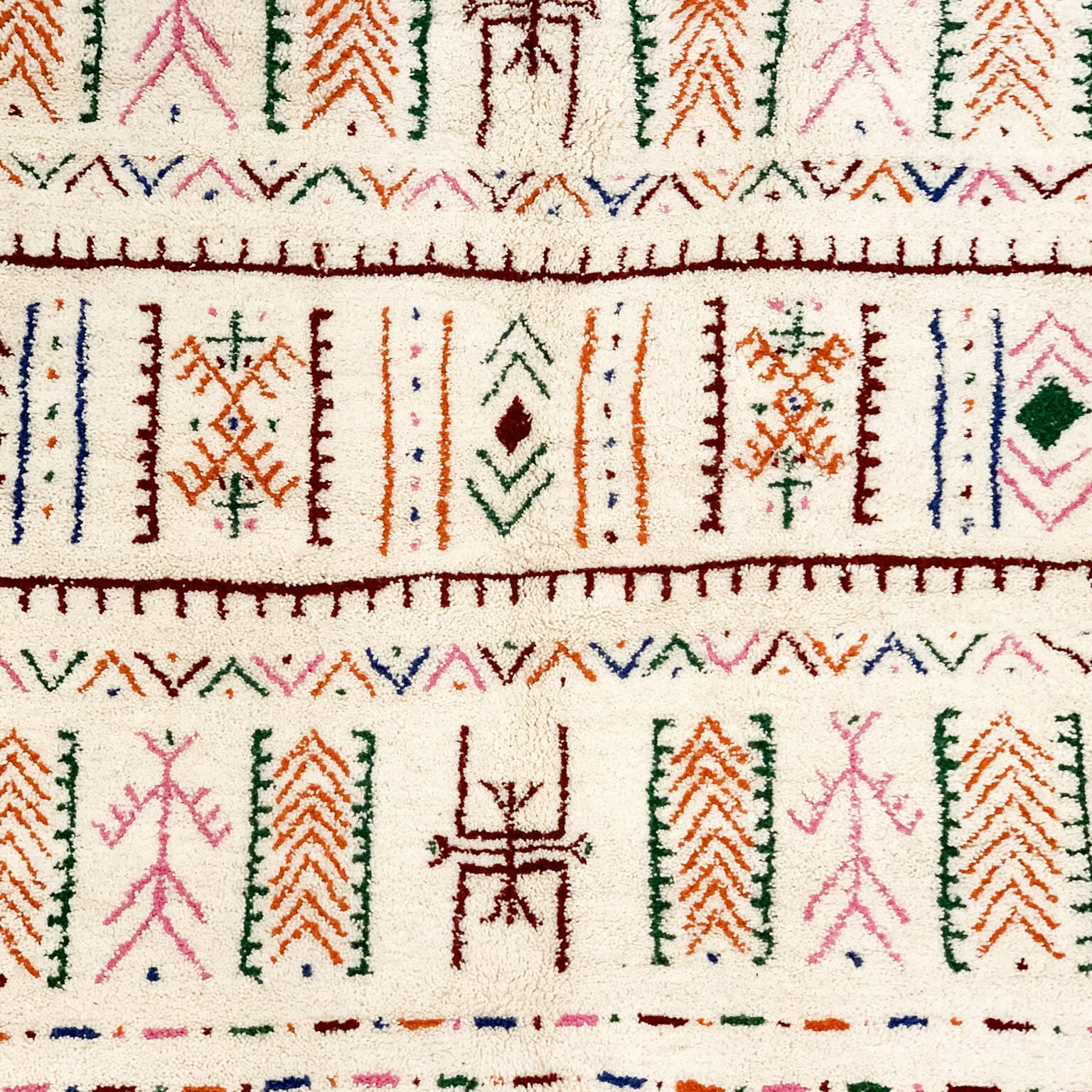 Tapis artisanal écru conçu par Afusart, tissé à la main par Malika, avec motifs amazighs noirs et touches colorées.