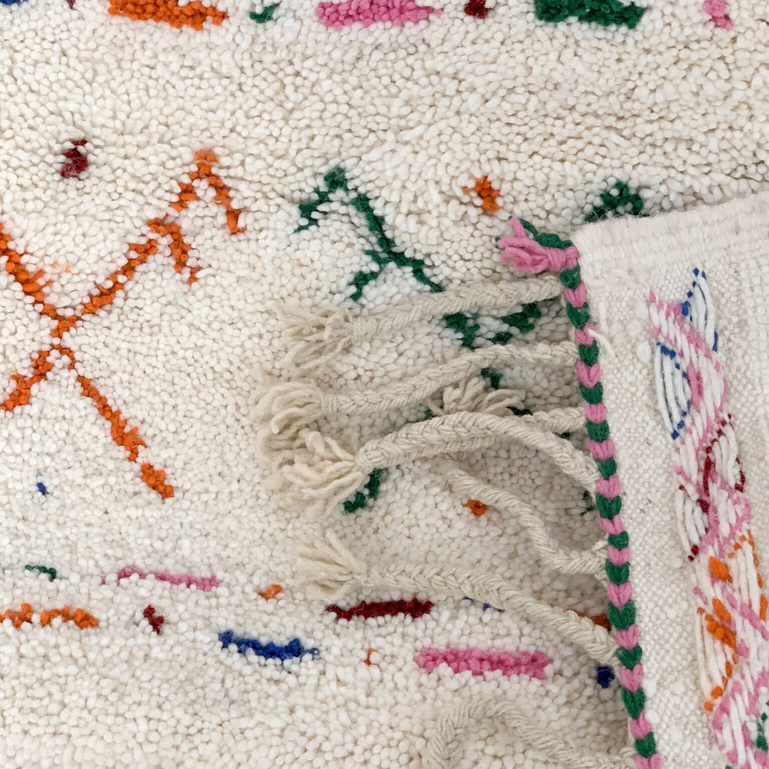 Tapis artisanal écru conçu par Afusart, tissé à la main par Malika, avec motifs amazighs noirs et touches colorées.